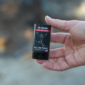 Hand holding a small black container labeled '55 Miles' Ultra Anti Chafe